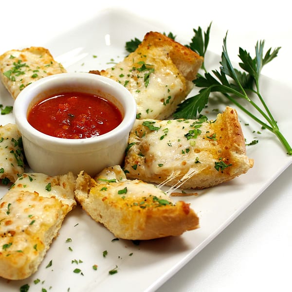 Cheesy garlic breadsticks with melted mozzarella and parsley, served with a side of marinara sauce.